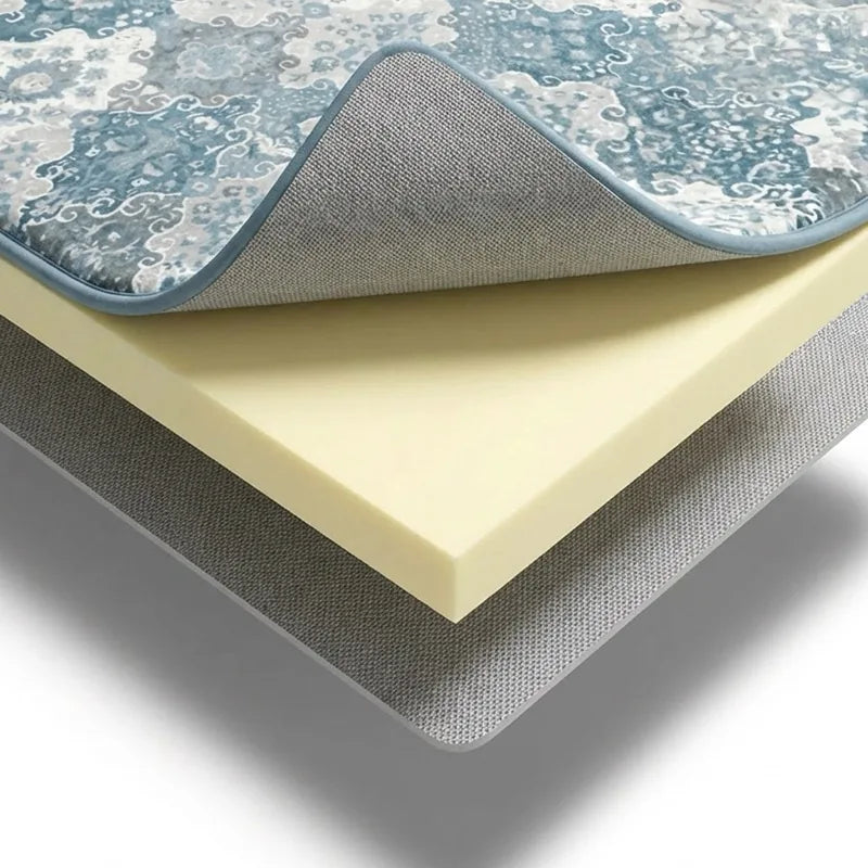 The three layers of a CloudMat separated and stacked: a patterned microfibre top peeled back off a thick cream foam core, sitting on a grey non-slip base