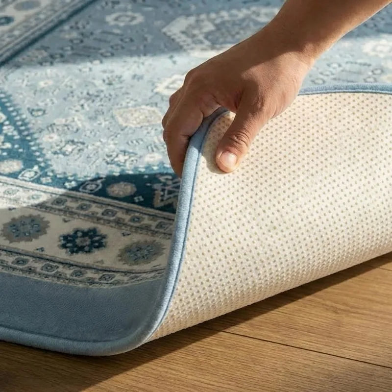 A hand lifting one corner of a CloudMat to reveal the textured non-slip backing underneath, the whole cushioned thickness curling over in a single bonded piece